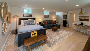 A spacious bedroom with a large bed, a sofa, and a desk area.
