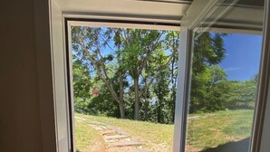 A doorway leading to a stone pathway with a grassy area and trees in the background.