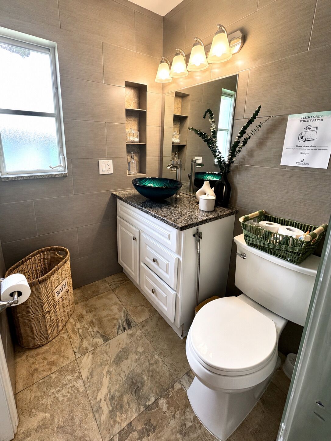 Une salle de bain avec des toilettes blanches, un lavabo vert, un miroir et un panier de papier toilette.