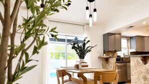 A modern kitchen with a dining area, featuring a large window, a potted plant, and a built-in oven. - House w/ Pool, Hot Tub & Backyard (Cape Coral)