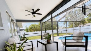 A covered patio with a ceiling fan, outdoor seating, a pool, and a view of the backyard. - House w/ Pool, Hot Tub & Backyard (Cape Coral)