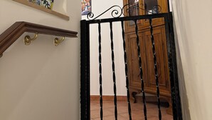 A staircase with a potted plant, a wooden cabinet, and a black gate. - The sweet little house (Palermo)