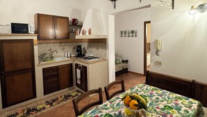 A kitchen with wooden cabinets, a dining table with a cactus tablecloth, and a small island with a sink and stove. - The sweet little house (Palermo)