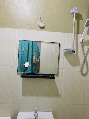 Un baño con espejo, lavamanos y ducha.