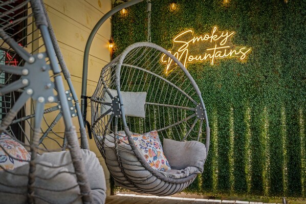A hanging chair with a cushion and a neon sign in the background.