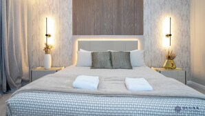 Een moderne hotelkamer met een groot bed, twee nachtkastjes en een hoofdbord met verticale lijnen.