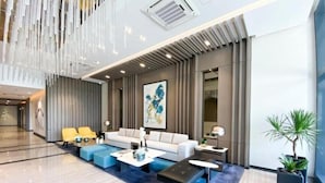 A modern lobby with a seating area, a large painting, and a potted plant. - Uptown Parksuites 2 (Taguig)