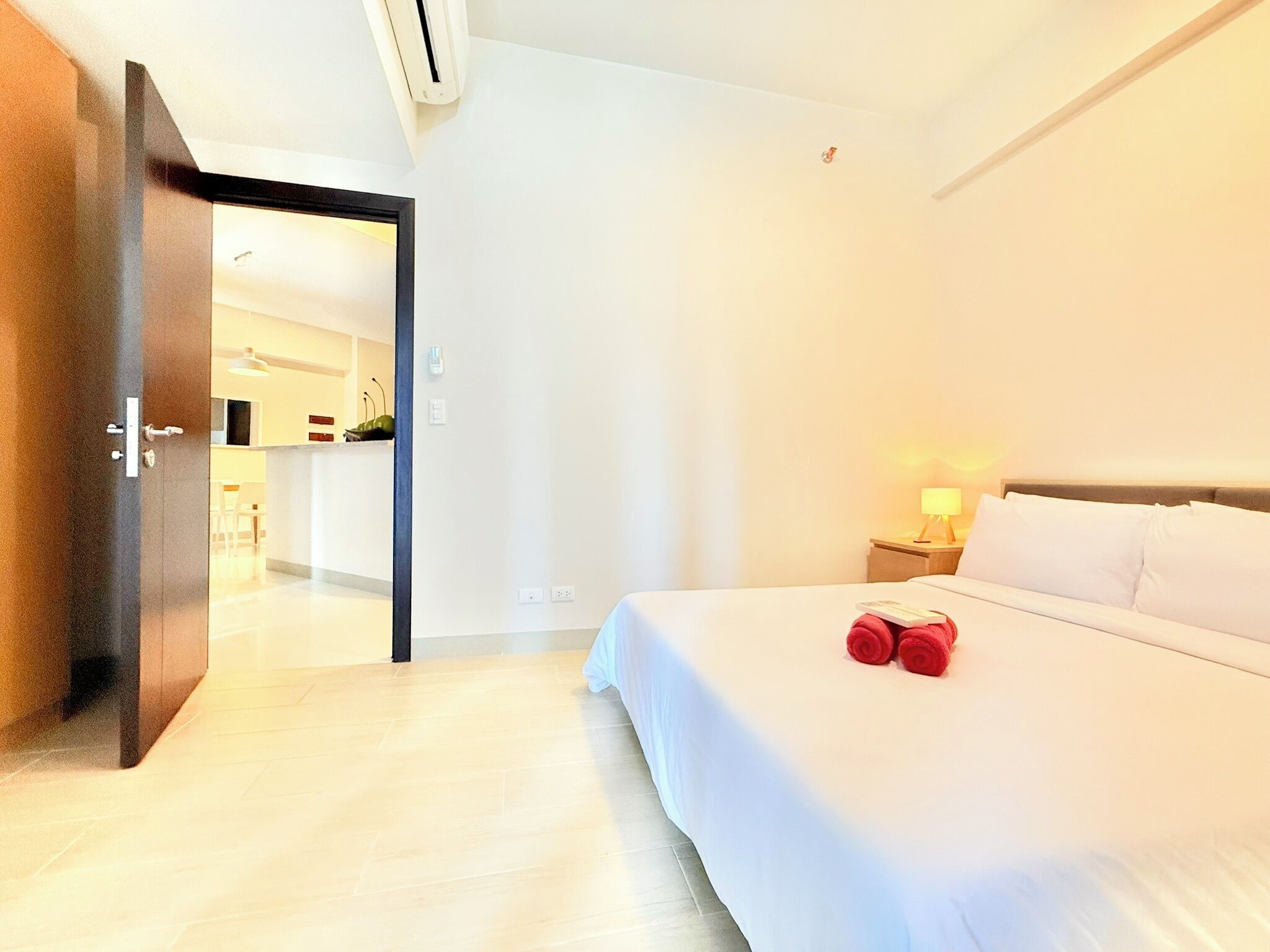 Une chambre d’hôtel comprenant un lit, une table de chevet, une lampe et une porte donnant sur une salle de bain.
