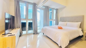A modern hotel room with a large bed, a flat-screen TV, and a desk. - Uptown Parksuites 2 (Taguig)