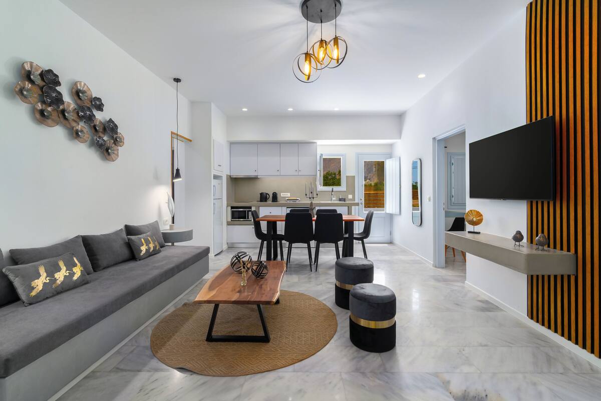 A modern living room with a sofa, coffee table, and ottomans, a dining area with chairs, and a kitchen in the background.