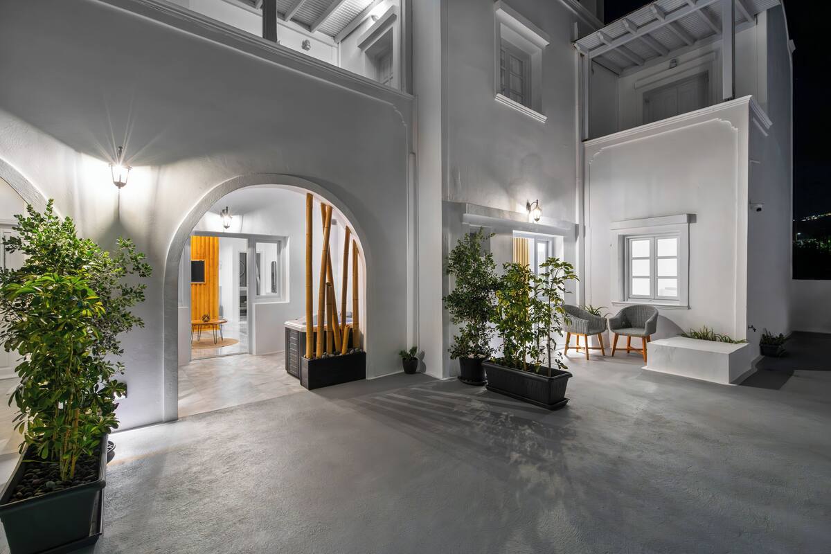 A spacious indoor area with a high ceiling, multiple arches, and potted plants.