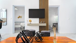 Ein modernes Wohnzimmer mit Flachbildfernseher, einem Holzes Esstisch und zwei Poufs.
