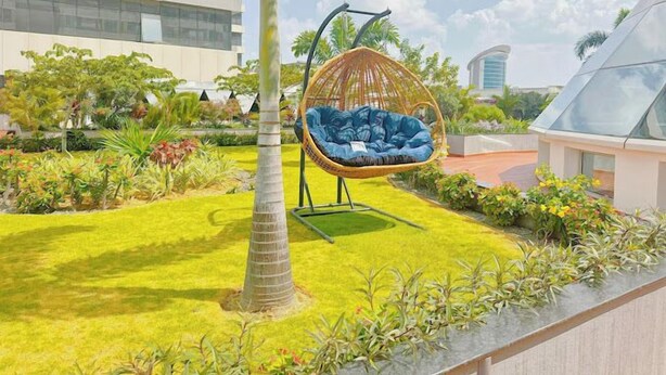 A modern building with a hanging chair in a well-maintained garden. - Kingjada Hotel  (Dar es Salaam)