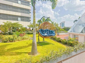 Un bâtiment moderne avec un fauteuil suspendu dans un jardin bien entretenu.