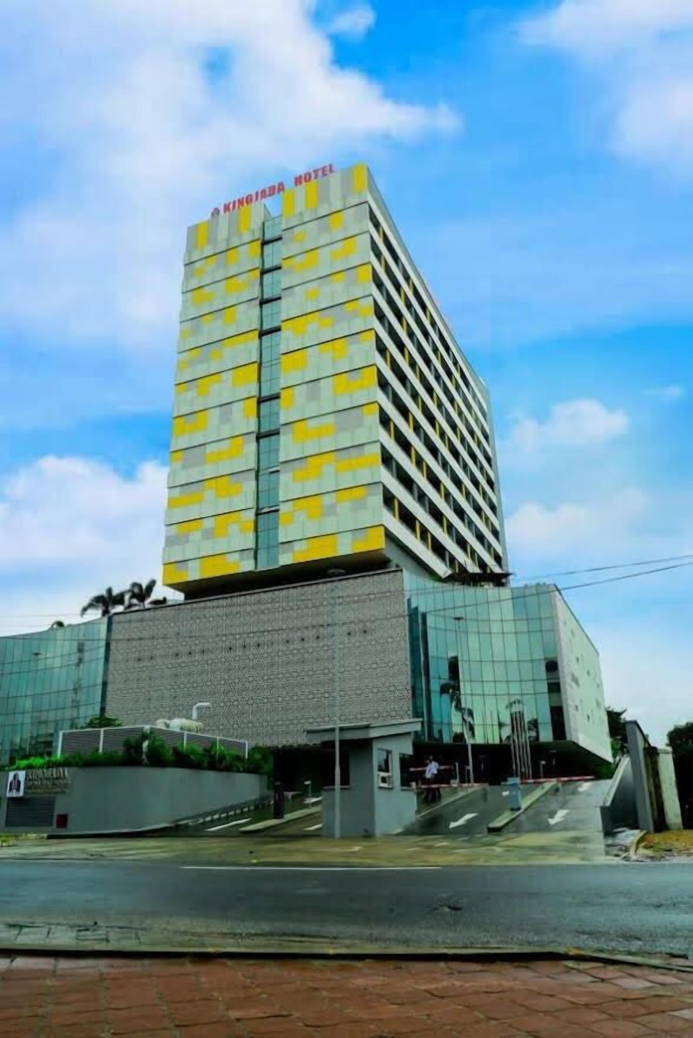 A tall hotel with a modern design, featuring a prominent yellow and grey facade and a clear sky in the background.