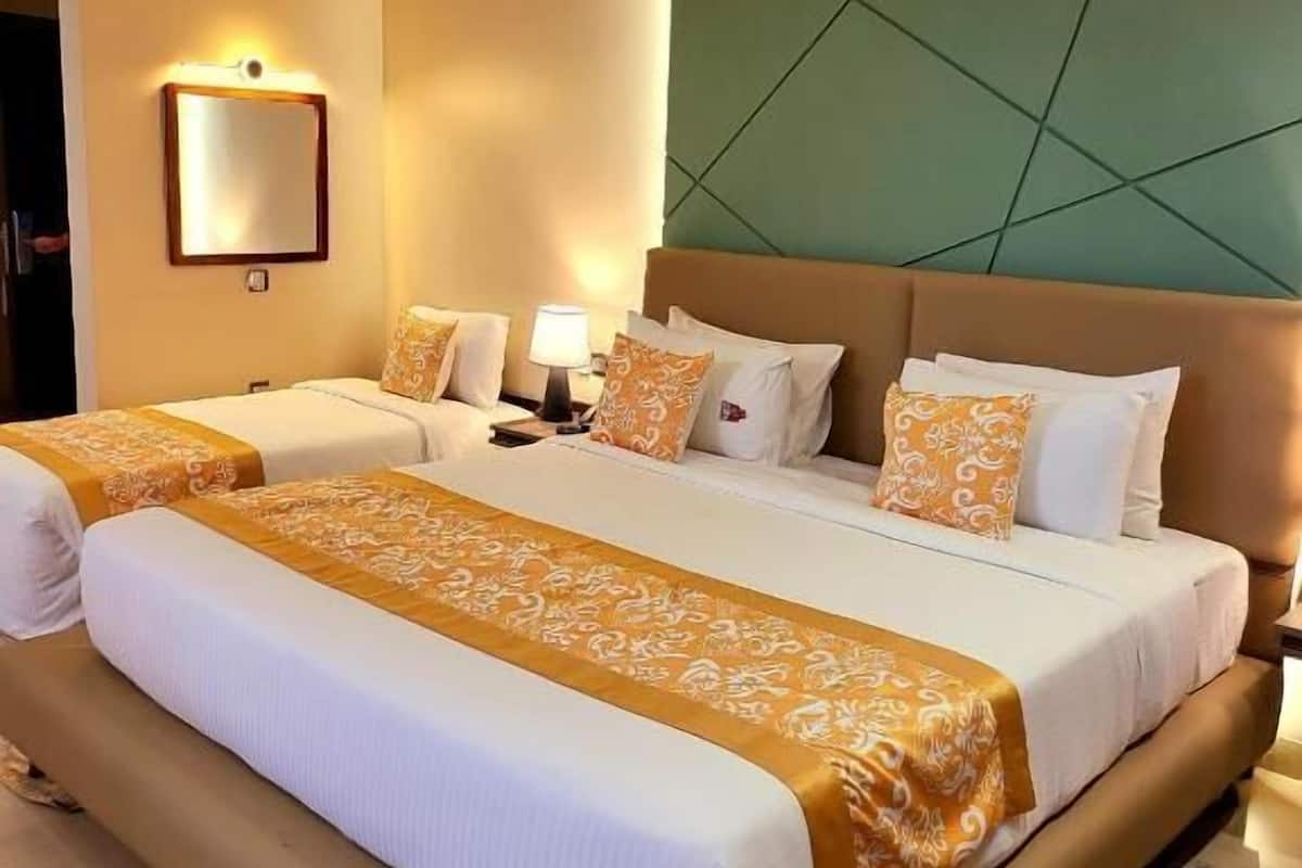 Ein Hotelzimmer mit einem großen Bett, zwei Nachttischen, einem Spiegel und einer Wand in Grünton.