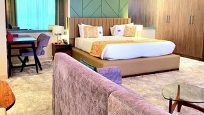 A hotel room with a large bed, a sofa, a desk, and a wardrobe. - Kingjada Hotel  (Dar es Salaam)