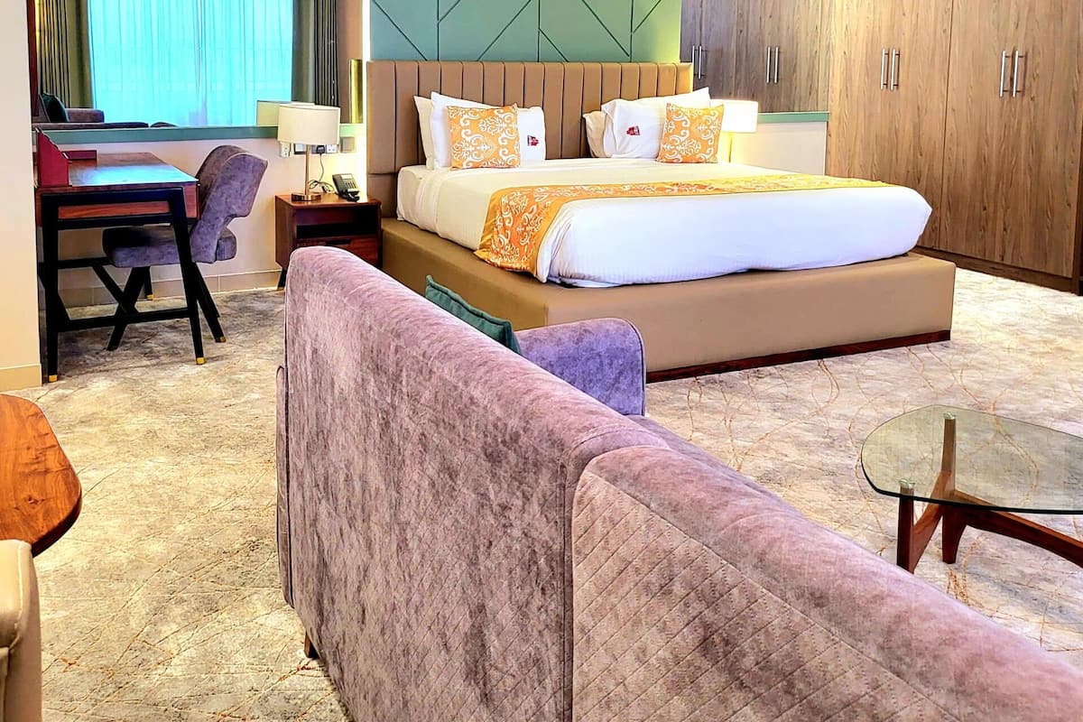 Ein Hotelzimmer mit einem großen Bett, einer Couch, einem Schreibtisch und einem Kleiderschrank.