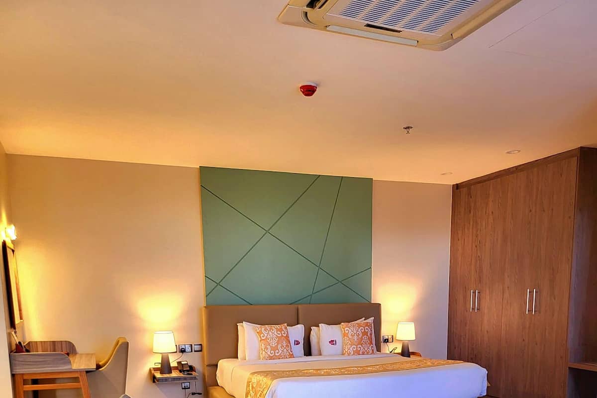 Ein modernes Hotelzimmer mit Bett, einer Sitzecke, einem Schreibtisch und einem Kleiderschrank.