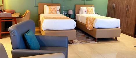 A hotel room with two beds, a sofa, a coffee table, and a desk.