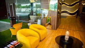 A modern lobby with yellow seating, a glass wall, and a wooden reception desk. - Kingjada Hotel  (Dar es Salaam)