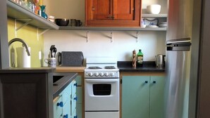A compact kitchen with a stove, oven, and a refrigerator. There are cabinets and a sink. The floor has a geometric tile pattern. - Private Downtown Apartment in Red Cloud, in the heart of Willa Cather country (Red Cloud)