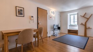 Una habitación con un escritorio de madera, dos sillas, un televisor, un teléfono y una ventana con vistas.