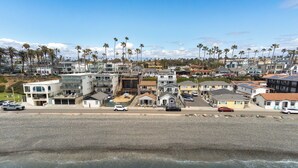 A coastal residential area with houses, a beach, and palm trees. - Beachfront Bliss | Shining Sea Condo on The Strand w/ Ocean Views (Oceanside)