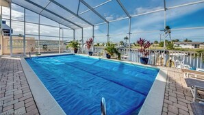 An indoor swimming pool with a clear view of the sky and surrounding buildings. - Paradise on the water w/ a pool & great fishing! (Saint James City)