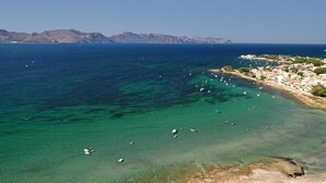 Una località costiera con acque cristalline, imbarcazioni e montagne sullo sfondo.