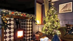Un salon chaleureux avec une cheminée, un sapin de Noël et un coin salon confortable.