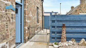 Un bâtiment en pierre avec une porte bleue, une enseigne indiquant « Going Coastal, 19 Church Street », et une clôture bleue avec un portail.