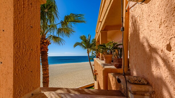 A view from a balcony overlooking a sandy beach with palm trees and the ocean. - Newly Remodeled, Great Views, Beachfront!  (San José del Cabo)