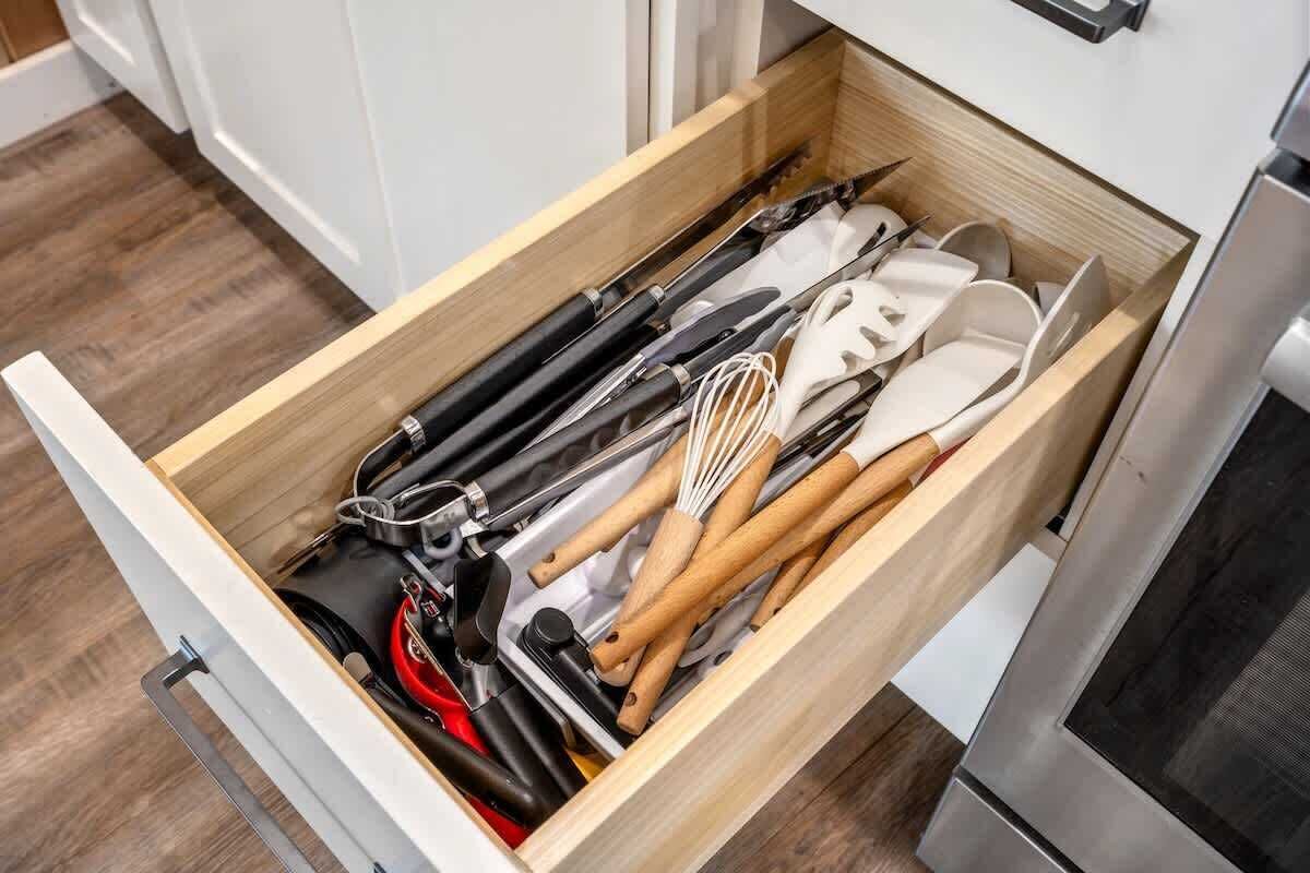 A kitchen drawer with various utensils and kitchen tools.