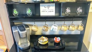 Ein Kaffee-Bereich mit einer Kaffeebar-Beschilderung, Kaffeesatzbehältern, einem Schild mit dem WLAN-Passwort und einem Schild mit der Aufschrift 'Nichtraucherbereich'.
