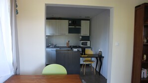 Una cucina compatta con mobili, un forno a microonde e un'area pranzo con tavolo e sedie.