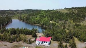 A cabin with a red roof surrounded by dense forest and a lake. - Beach Bliss (Boylston)
