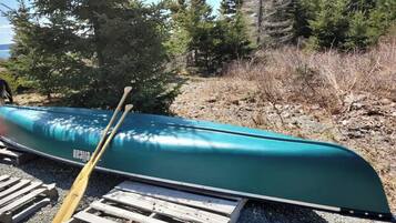 A canoe on a wooden pallet outdoors with trees in the background.