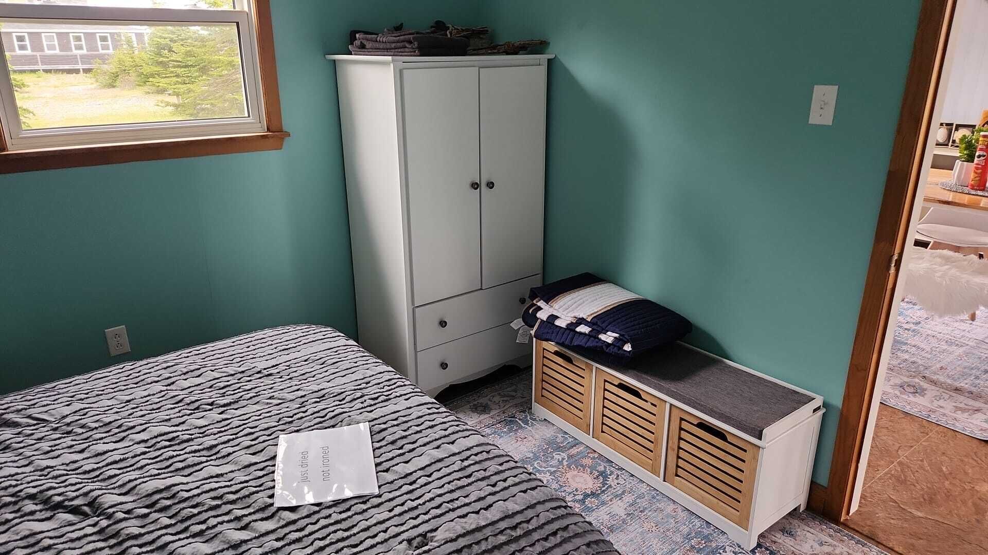 A bedroom with a bed, a wardrobe, and a small cabinet.