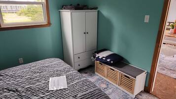A bedroom with a bed, a wardrobe, and a small cabinet.