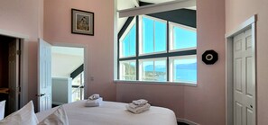 A bedroom with a large window, a bed with towels, a door, and a framed picture on the wall. - La Casa Lakeside Resort (Kelowna)
