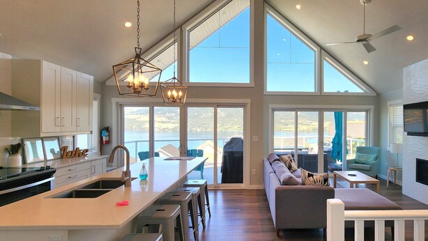 Uma cozinha espaçosa com uma ilha grande, uma área de jantar com vista e uma sala de estar com sofá e televisão.