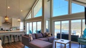 Uma cozinha ampla com uma ilha grande, banquetas e vista para o lago.