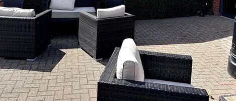 An outdoor seating area with wicker furniture and a wall with the text "the terrace".
