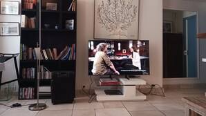 Un salon comprenant un téléviseur, une bibliothèque et une œuvre d’art encadrée représentant un arbre.