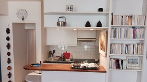Une cuisine moderne avec des meubles blancs, un plan de travail en bois et une bibliothèque remplie de livres.