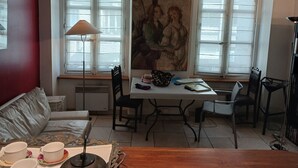 Un salon confortable avec un canapé, une table à manger entourée de chaises, une lampe et un tableau accroché au mur.
