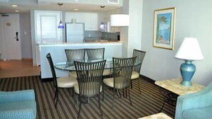 A compact living space with a dining area, kitchenette, and a small seating area with a lamp.