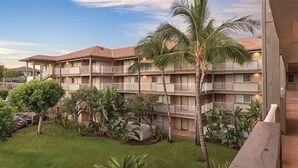 A multi-story hotel with balconies, surrounded by lush greenery and palm trees.