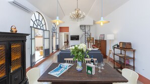A dining area with a wooden table, chairs, a vase with flowers, and a chandelier. - Amazing Penthouse Prati (Roma)
